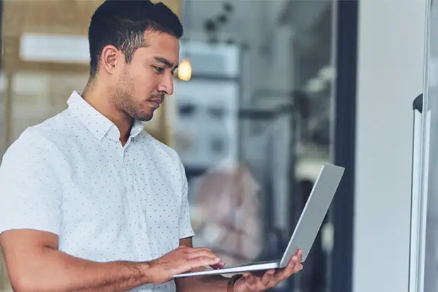 A man in a white shirt using a laptop