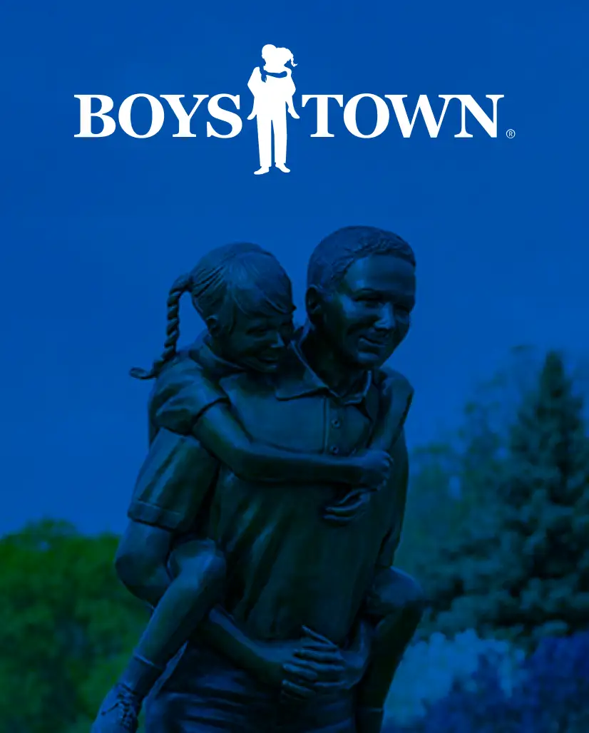 Bronze statue of a child on a mans back playing together with the Boys Town logo