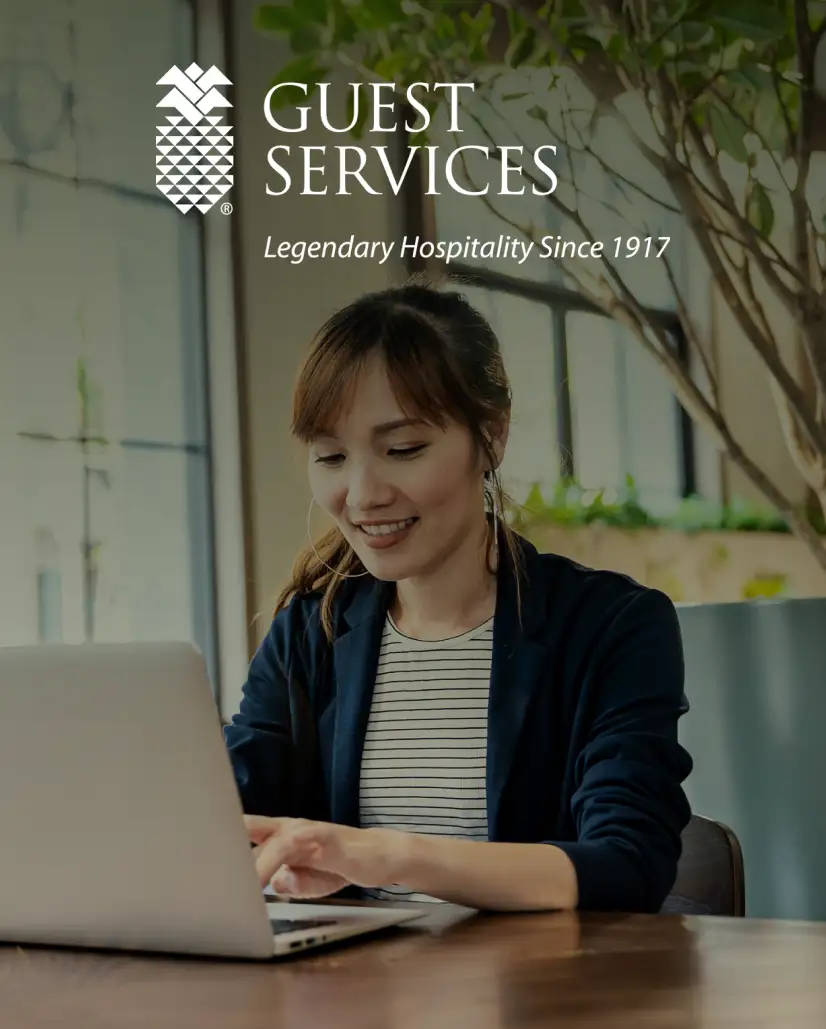 A woman sitting in front of a laptop computer, Guest services logo