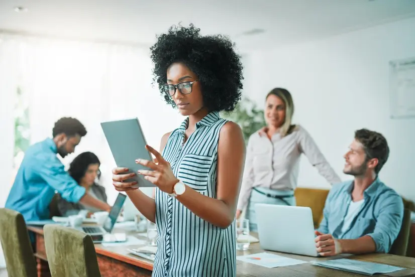 A woman standing with a tablet computer during a meeting